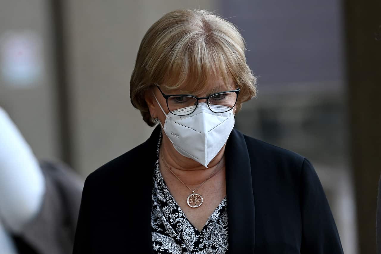 A woman wearing a face mask and looking down.