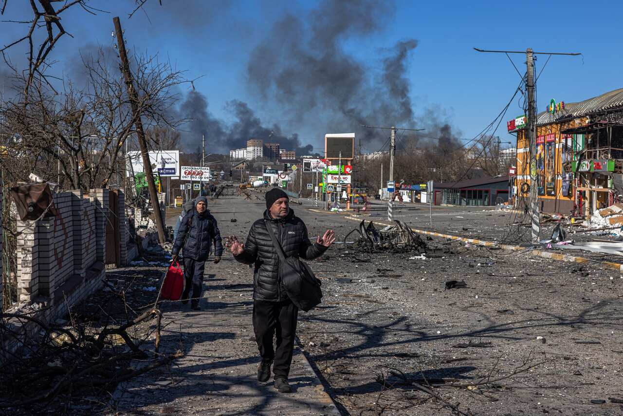 Residents coming from Bucha town, which is currently controlled by the Russian military, walk with luggage towards the Ukrainian checkpoint.