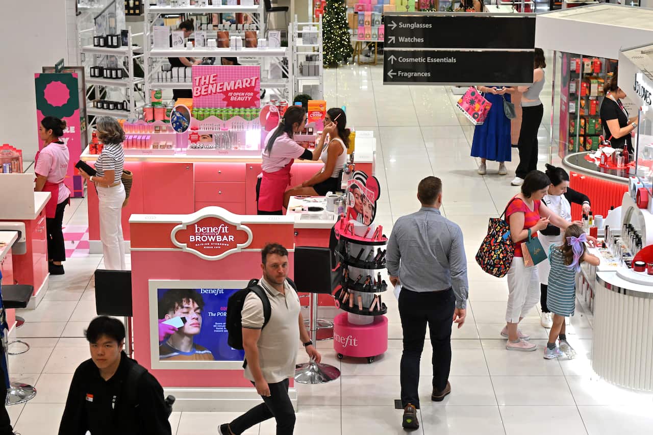 Top view of a department store. People walk past a Benefit browbar decked out in pink decorations and perfume counters