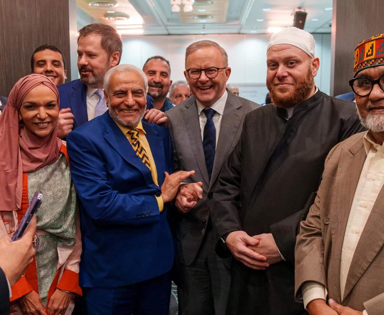 Muslim figures pose together with Anthony Albanese, smiling. 
