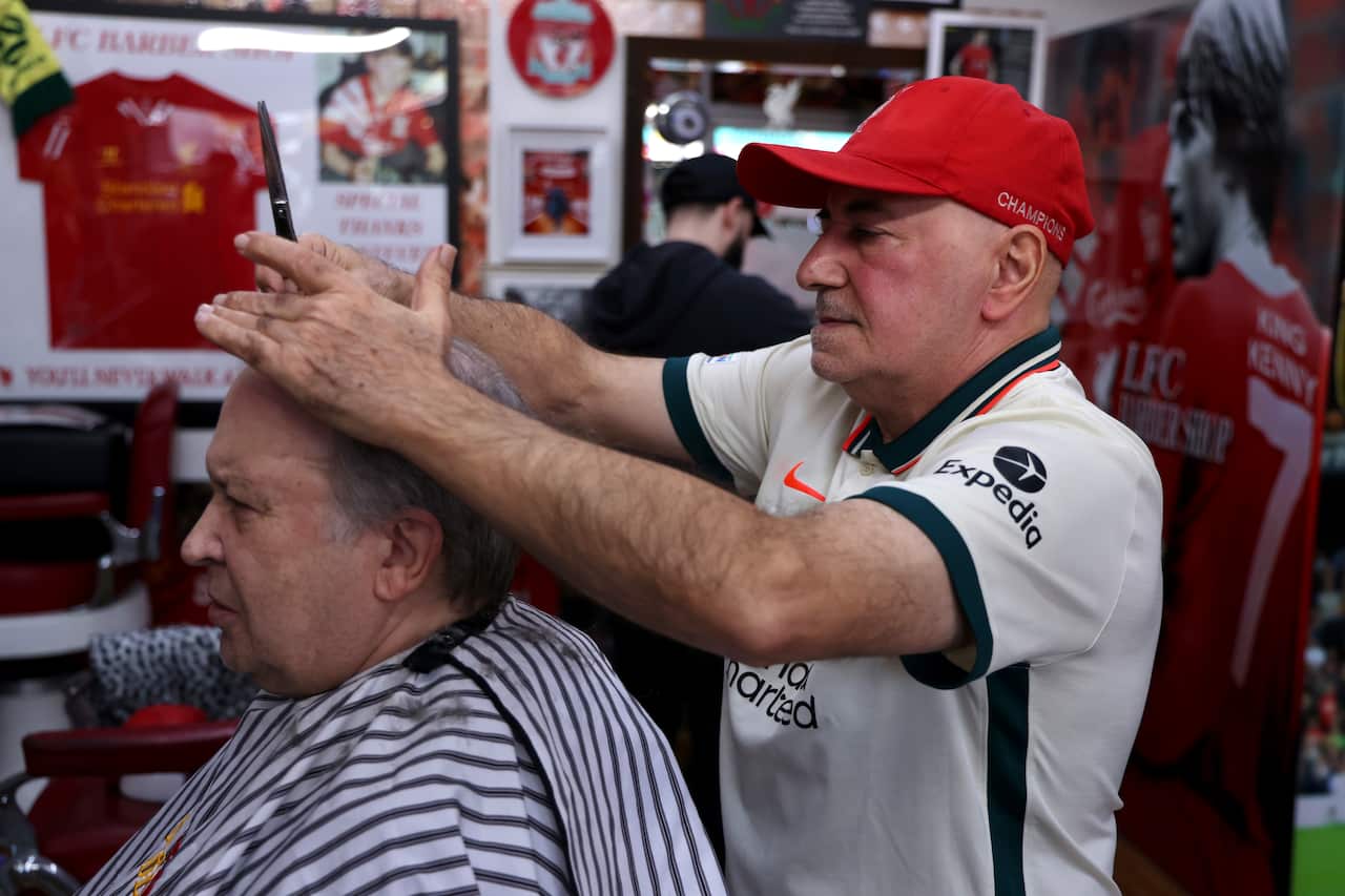 Kleames Dawod (right) gives his longtime friend Michael Shedrinsky (left) a haircut inside his Liverpool-themed barbershop in Sydney.