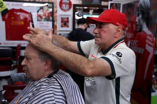 Kleames Dawod (right) gives his longtime friend Michael Shedrinsky (left) a haircut inside his Liverpool-themed barbershop in Sydney.