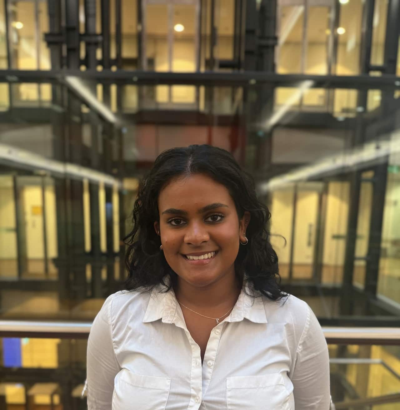 A woman with a cream shirt standing inside