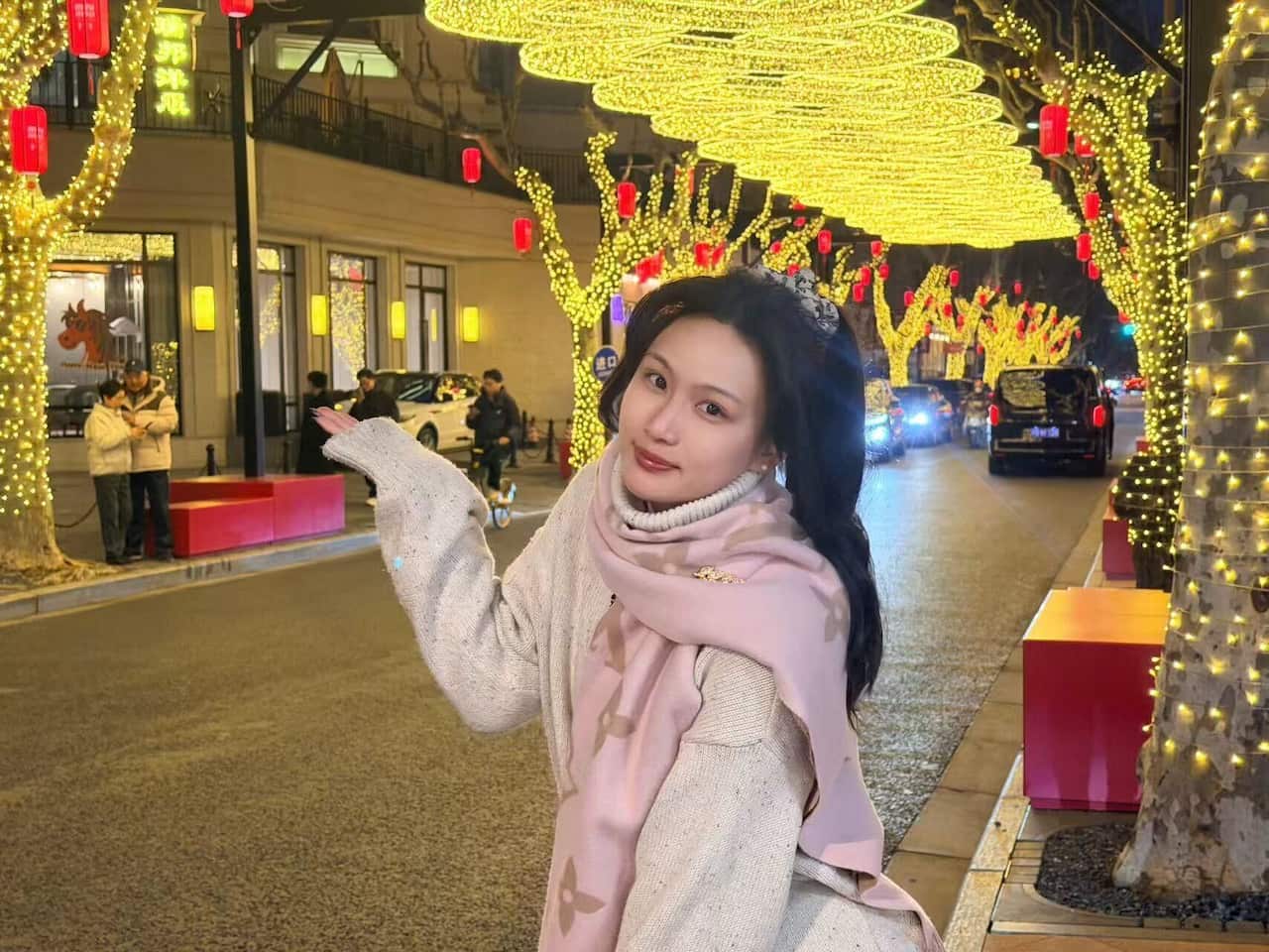 Woman standing below festive lights