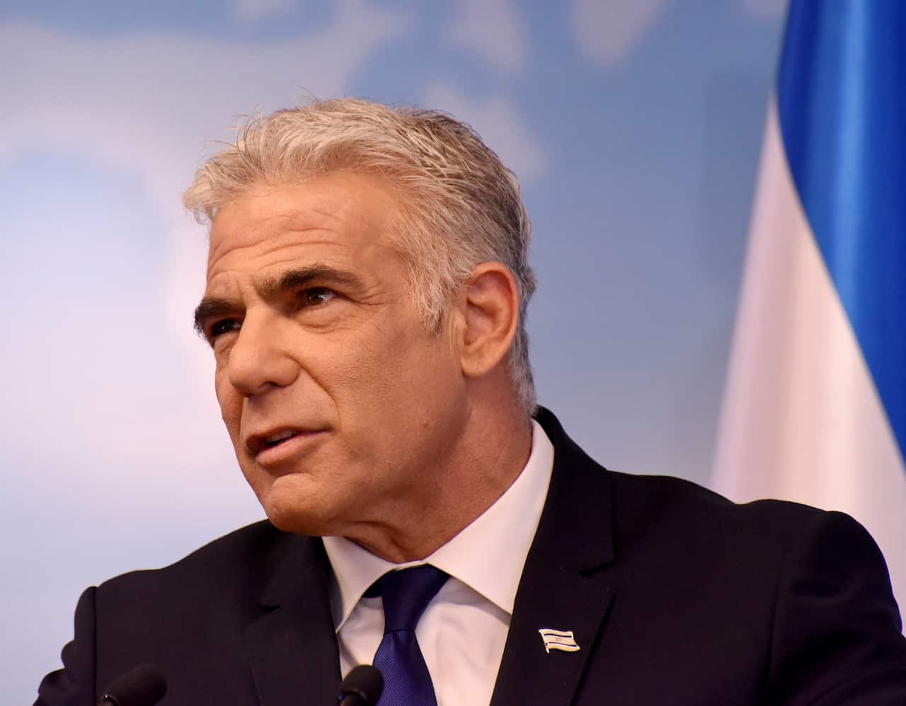 Israeli Foreign Minister Yair Lapid in a suit looking away from camera. 
