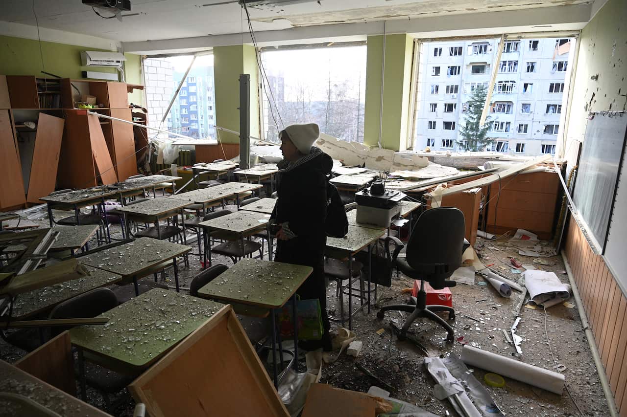 A person inspecting a classroom that has been destroyed