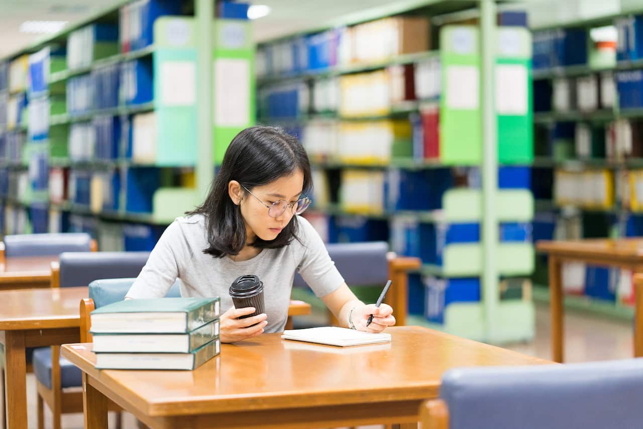 A woman writes in a library.