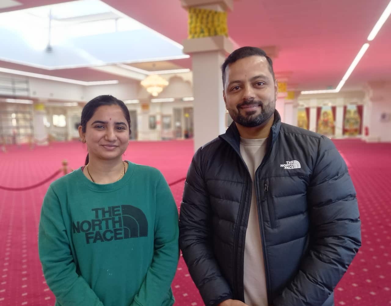 A woman and a man standing inside a Hindu temple.