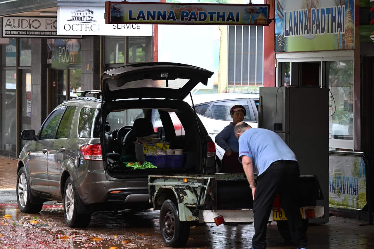 A man loading a trailer parked outside a store.