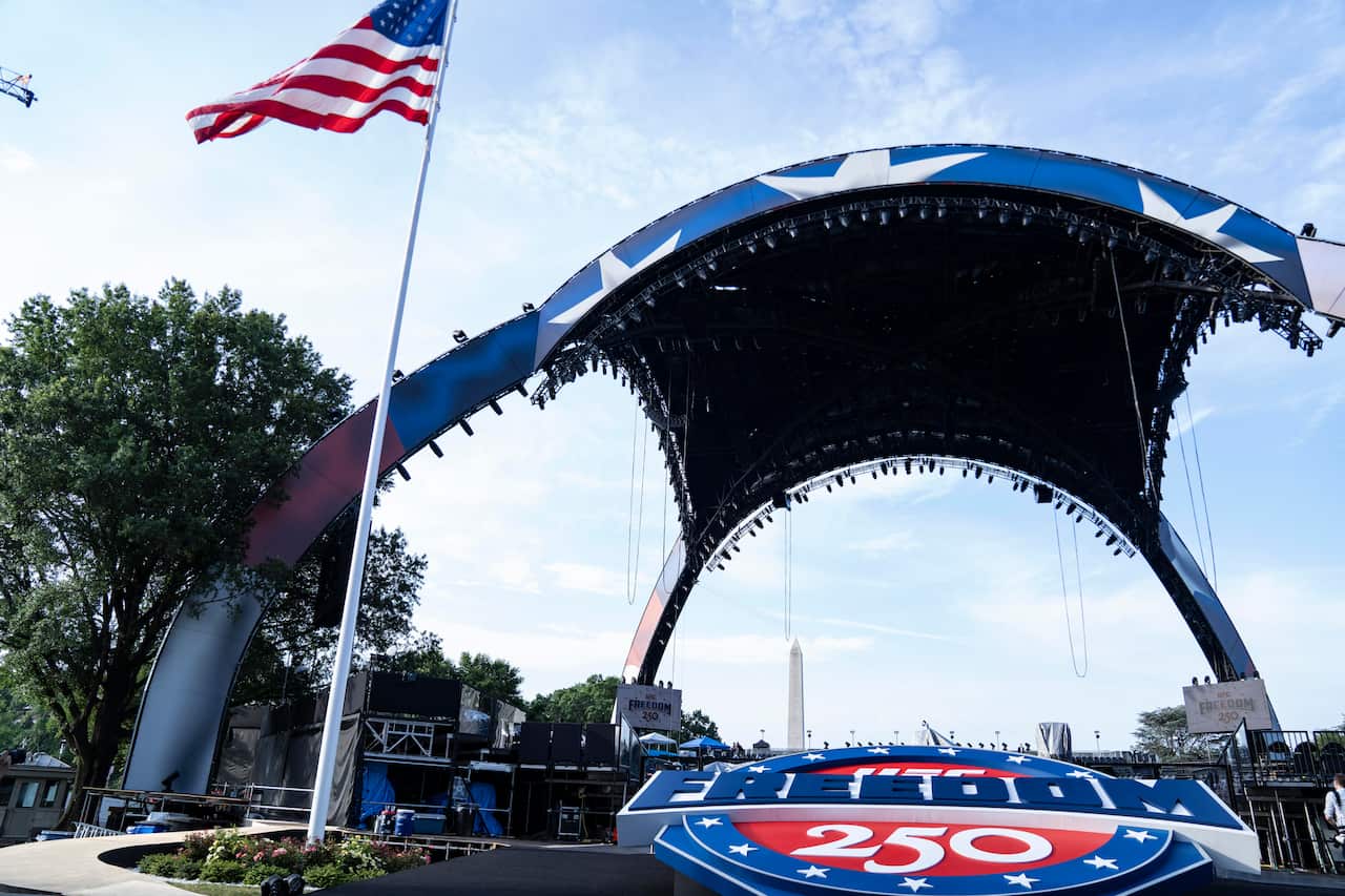 A large canopy with a US flag in front of it. A large plaque with the words "Freedom 250" written is below it.