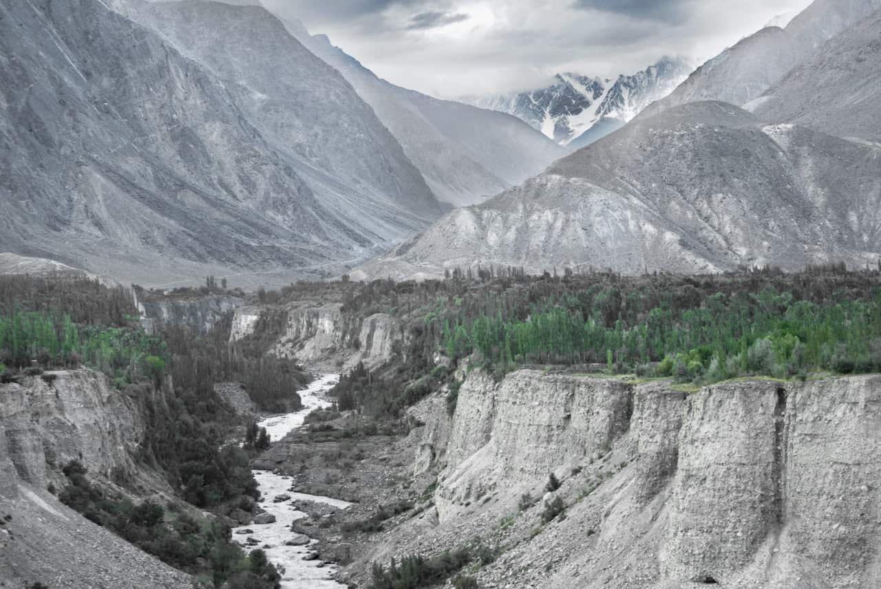 A landscape shot of a river running through a valley with a backdrop of mountains