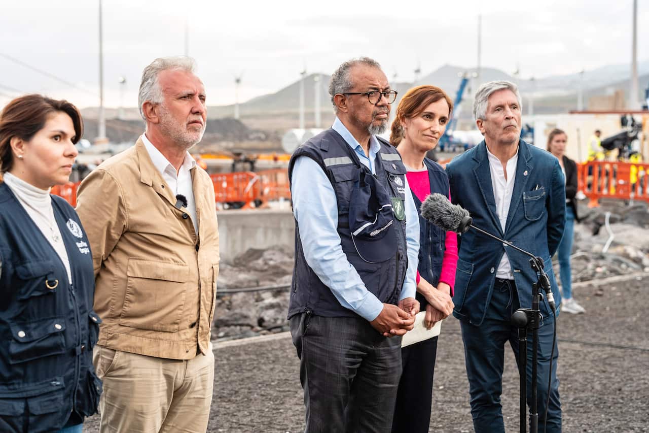 A group of people, three men and two women, standing beside each other at a press conference at a port.