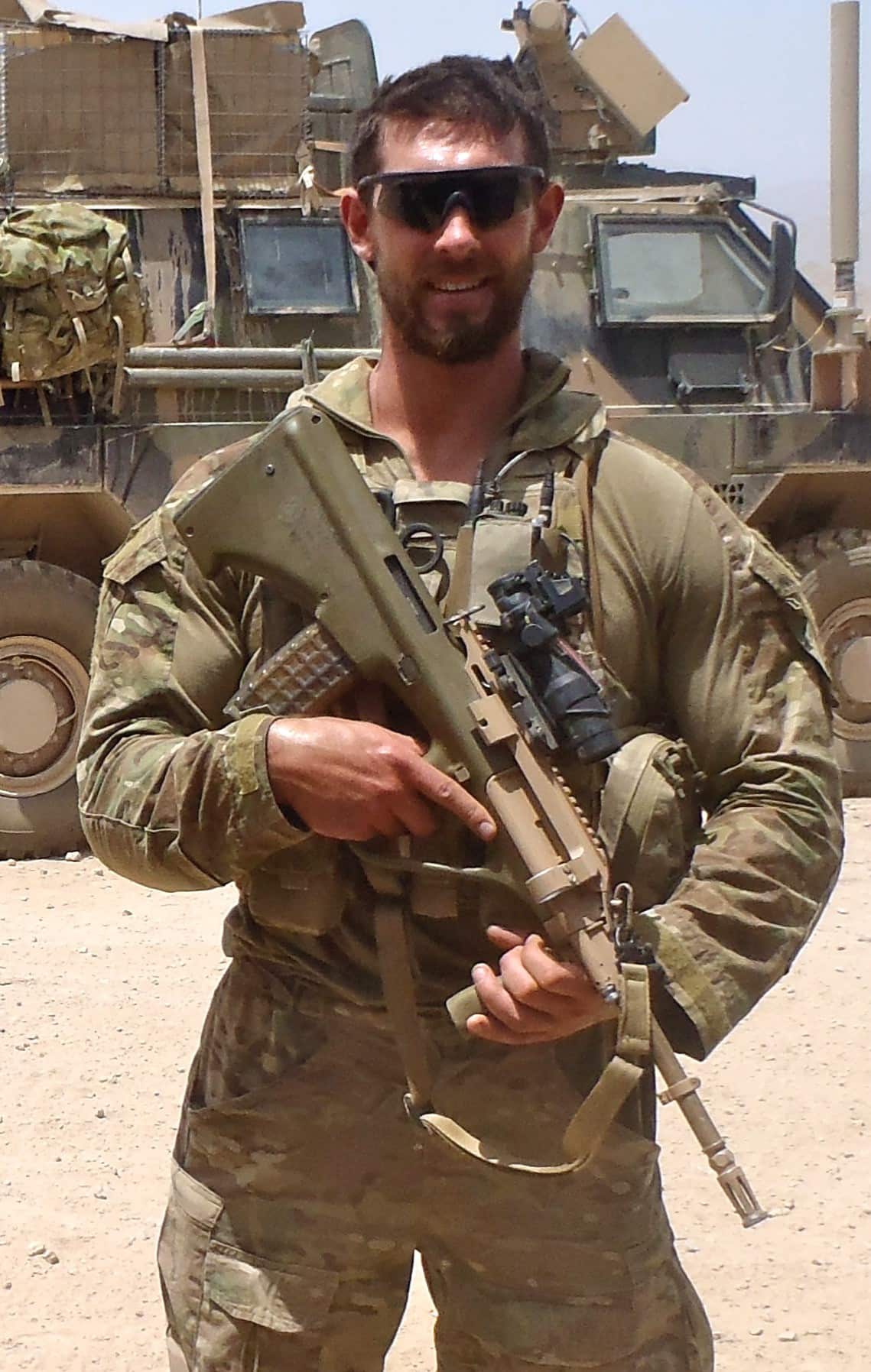 A photo of a male soldier wearing army fatigues posing with a rifle 
