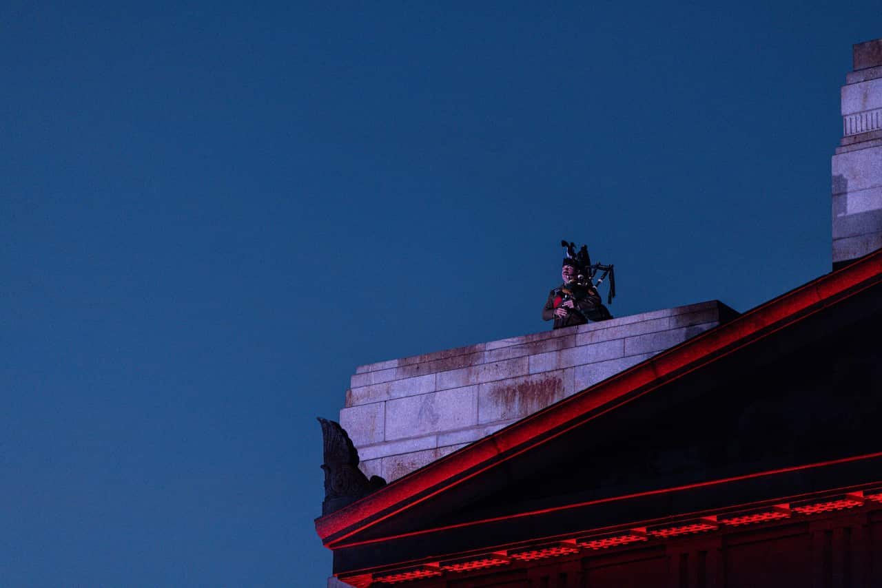 A person playing a bagpipe on top of a memorial building.