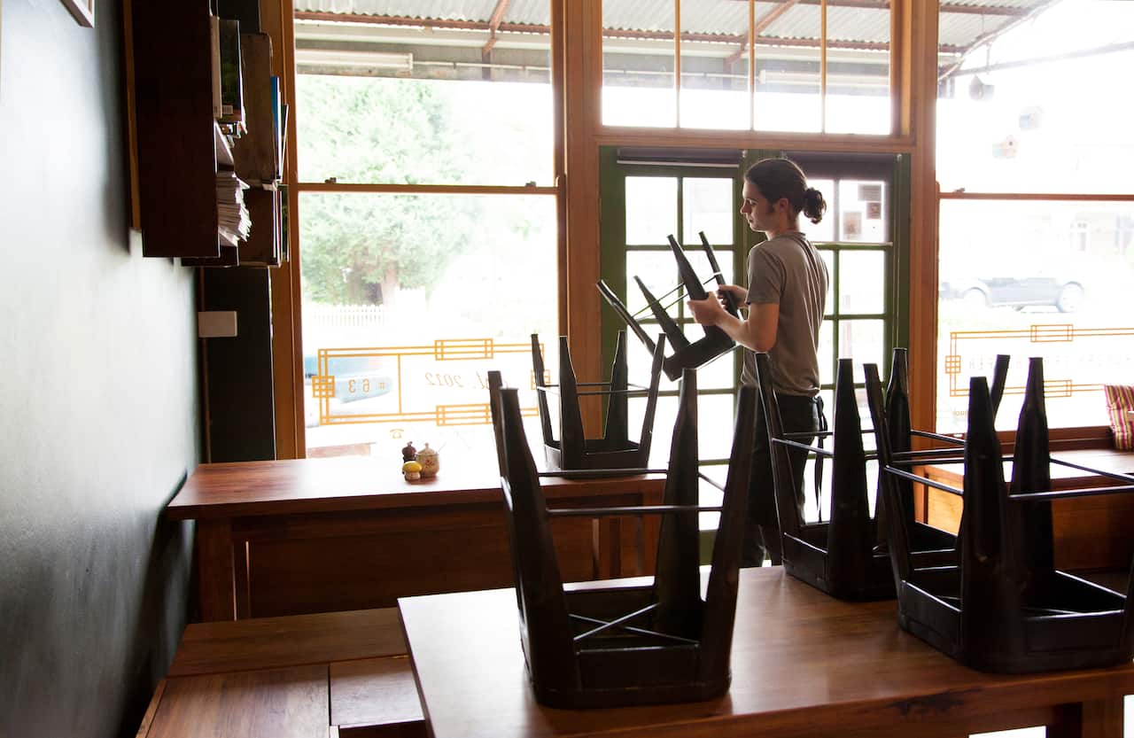 Waiter packing up chairs at a restaurant.