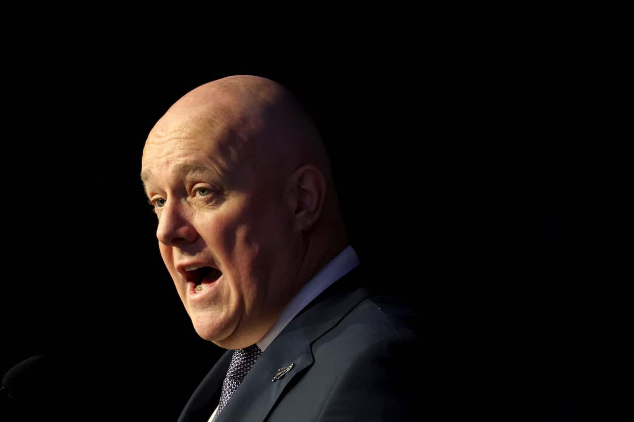 New Zealand Prime Minister Christopher Luxon speaks in a dark room.