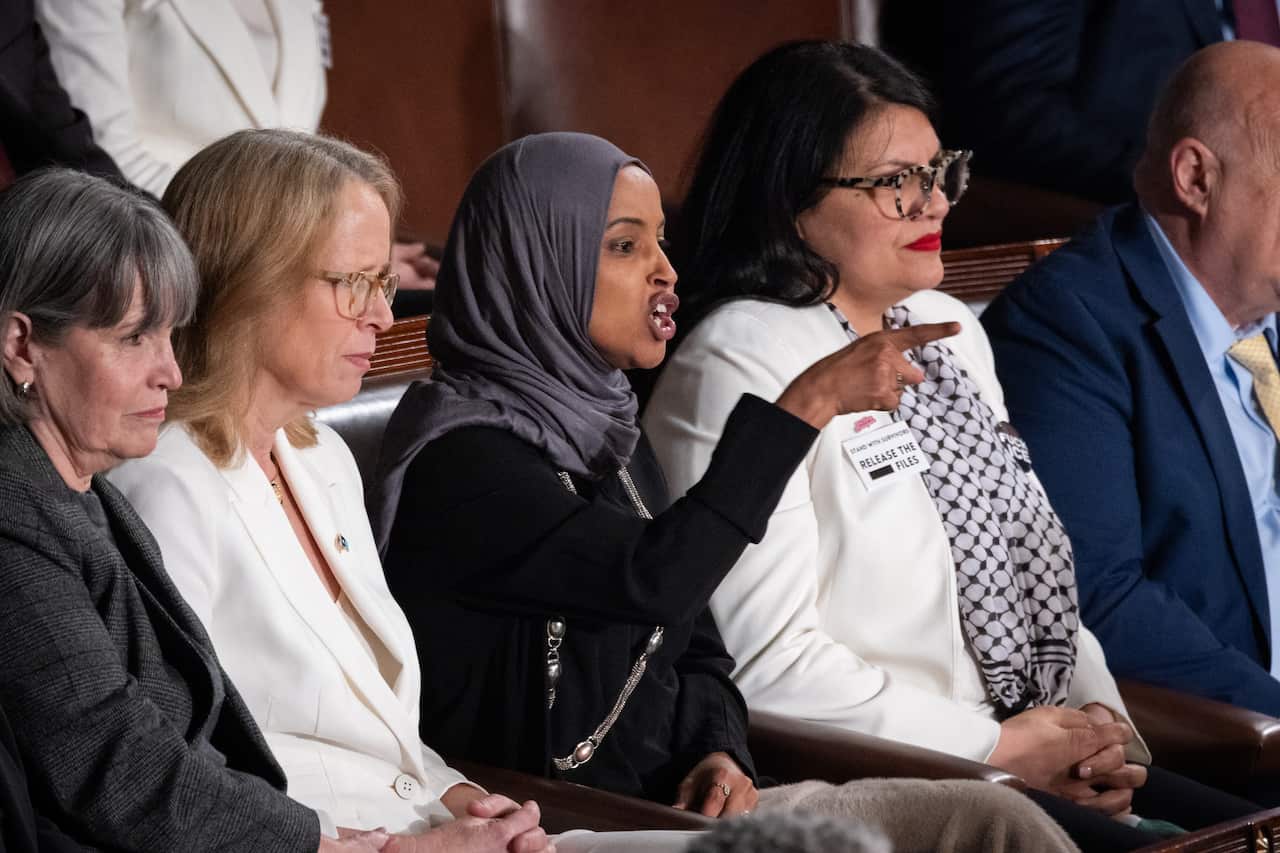 A row of people sitting on a bench together. One woman is pointing and shouting.