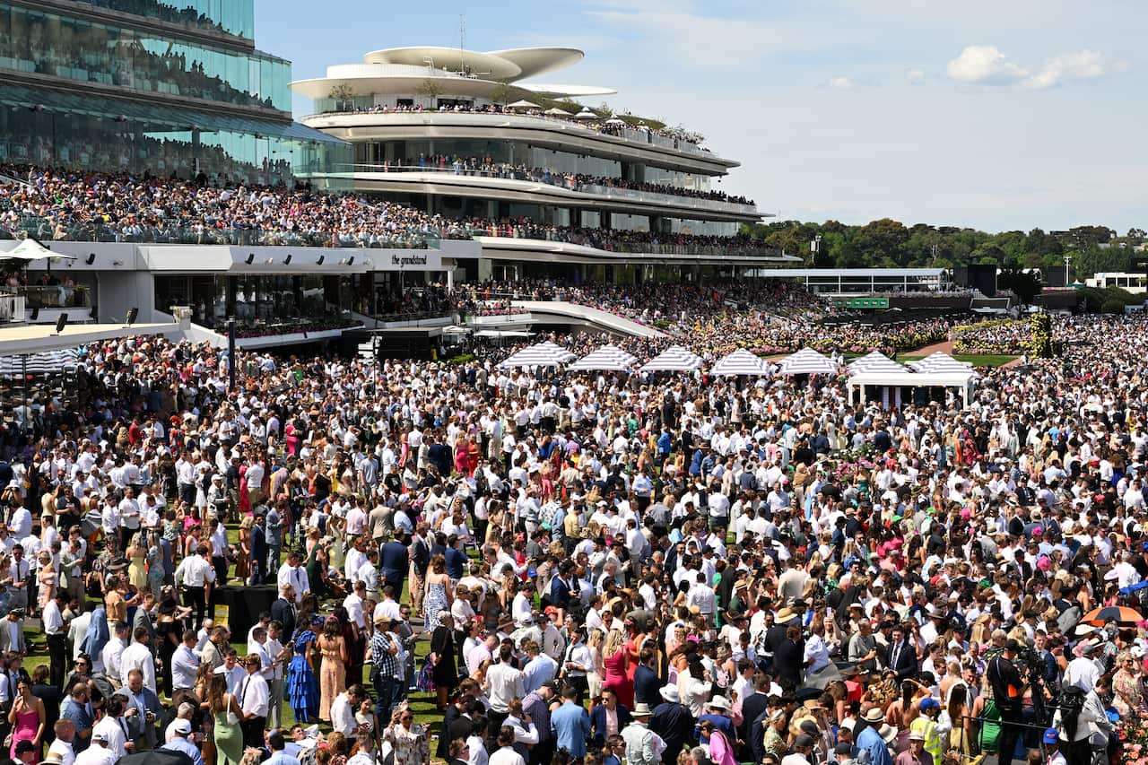 A very large crowd of people outside glass three-storey buildings