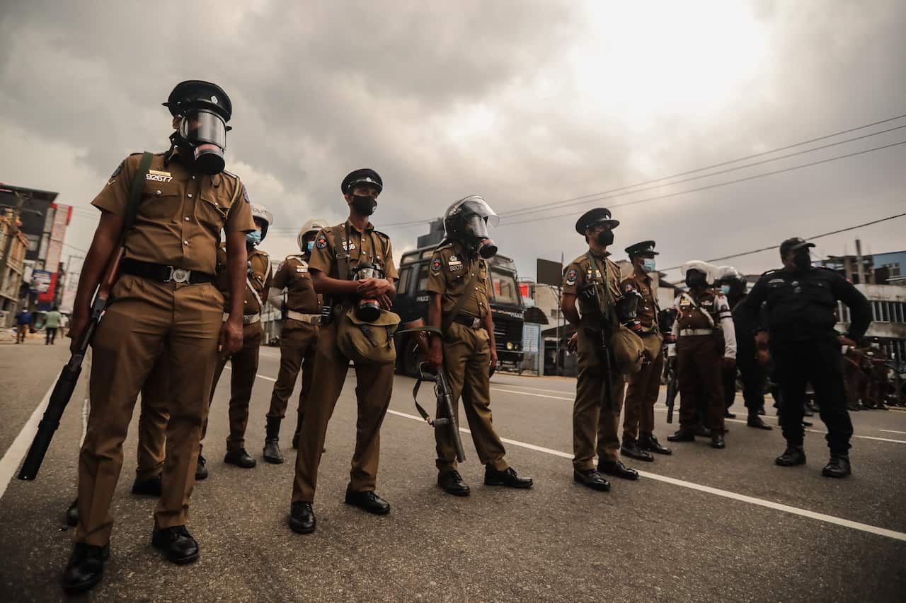 Sri Lankan riot police are seen standing guard.