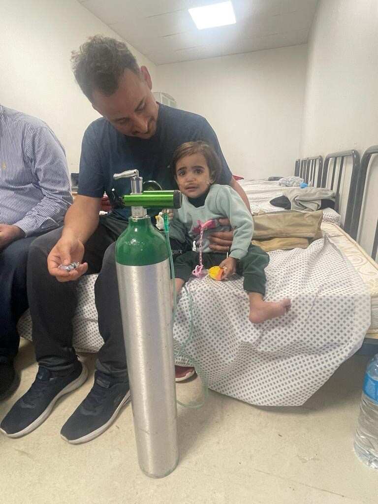 Little girl patient girl receives oxygen while sitting on the bed in the European hospital in Gaza