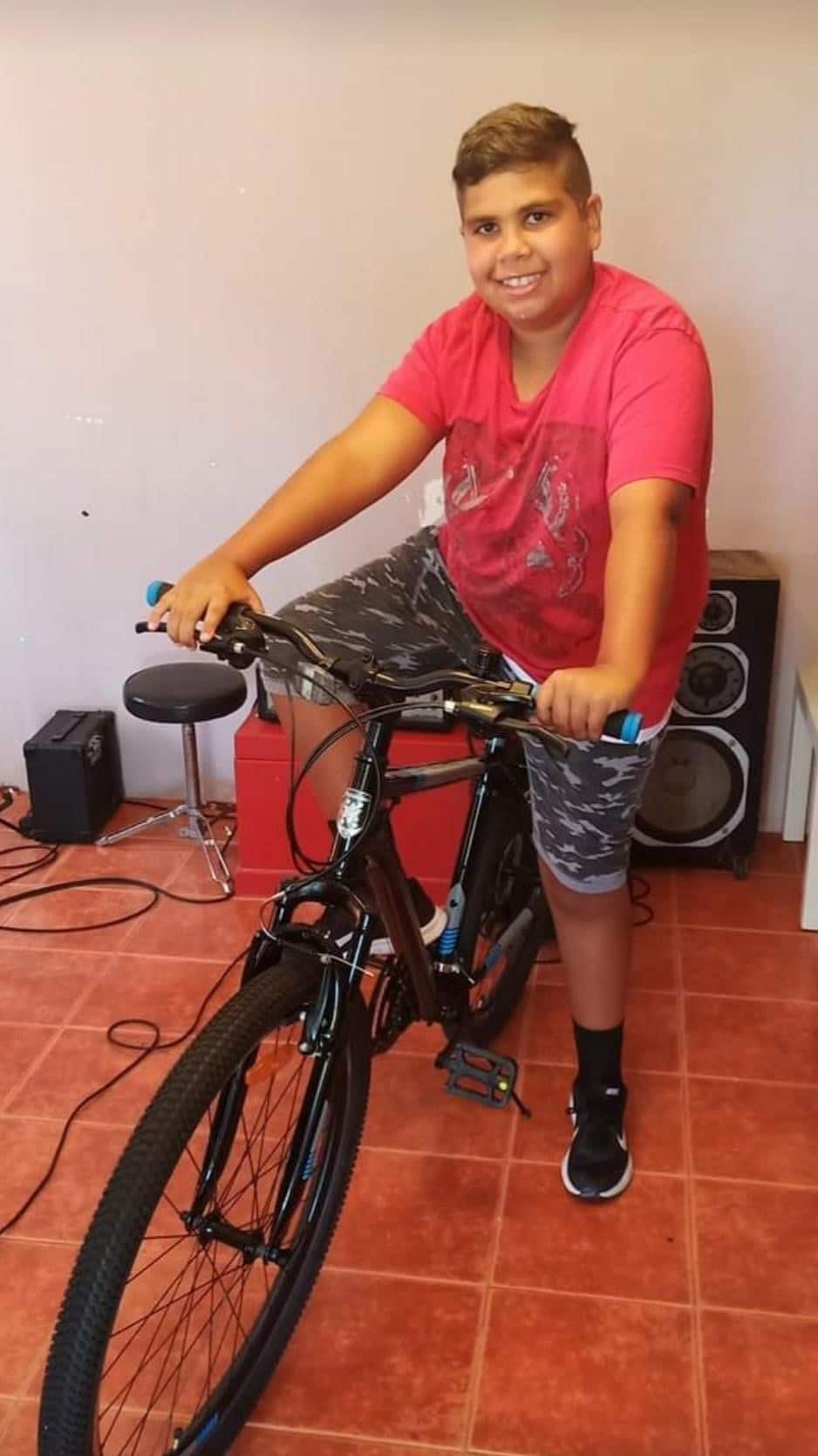 Teenage victim Cassius Turvey in a red t-shirt and grey shorts on a black bicycle