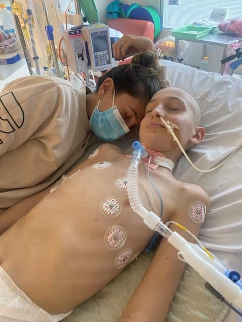 A mother lies next to her sick son on a hospital bed.
