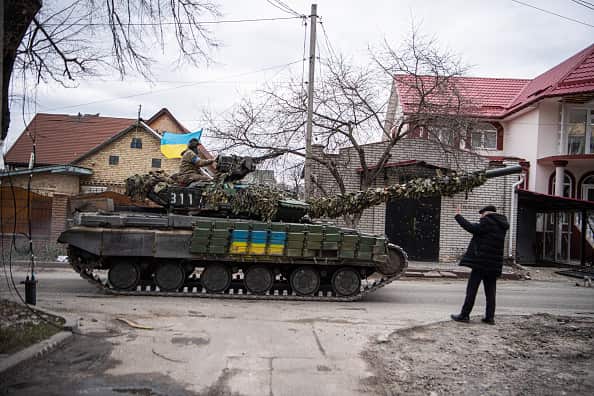 A man waves at a Ukrainian army tank as it drives on a street in Irpin, near the capital Kyiv. 