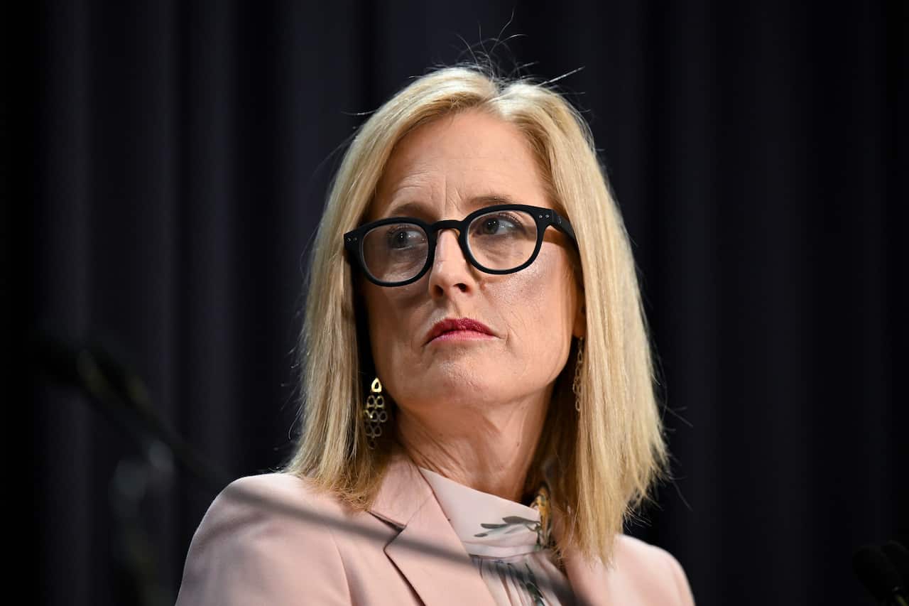 A woman wearing glasses looks on at a presser.