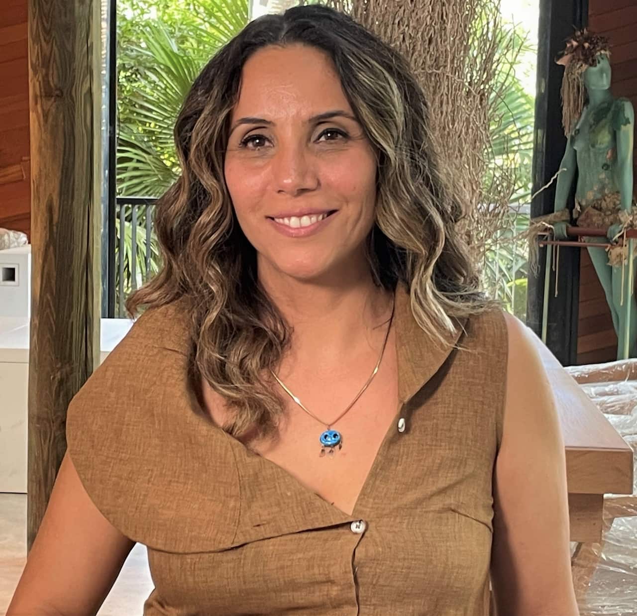 A woman in a brown dress sitting in a lounge room.