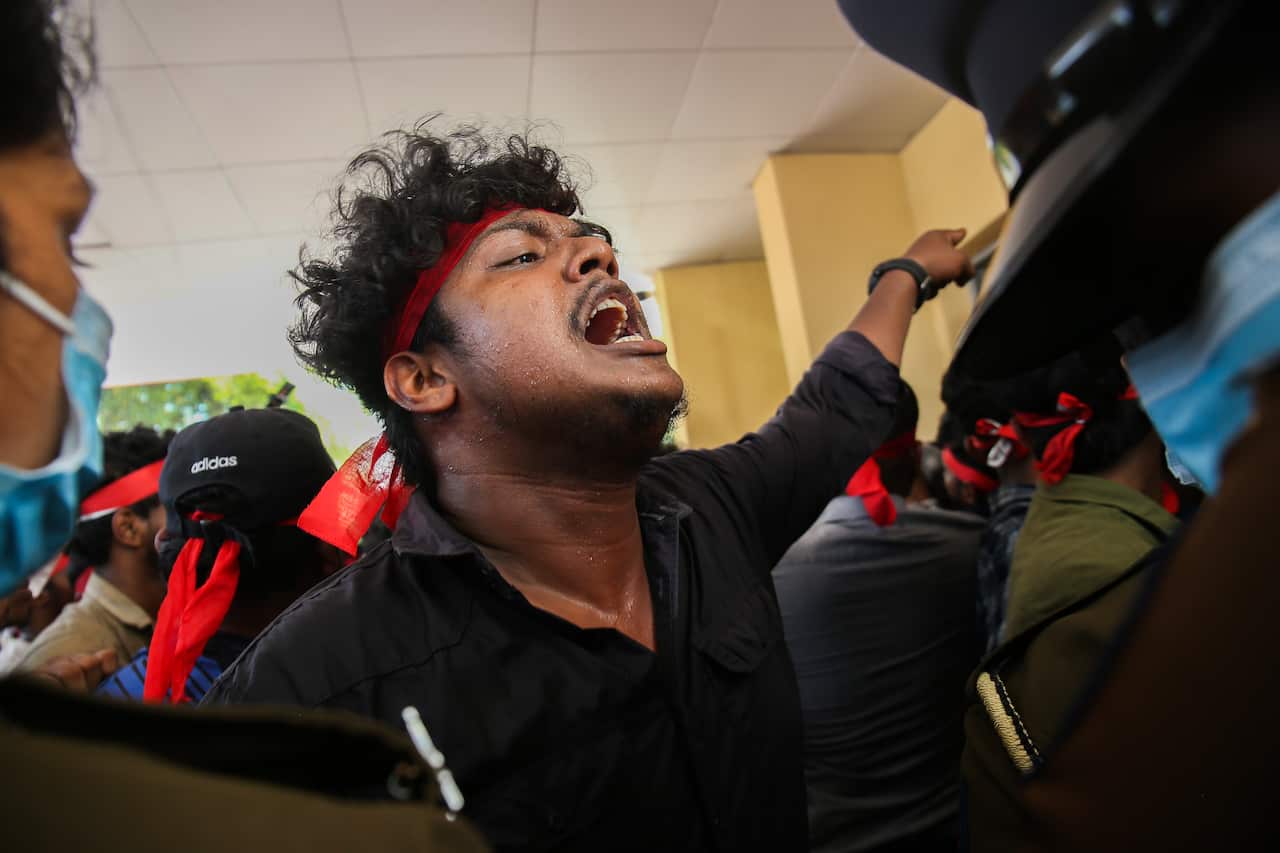 A man among a crowd of protesters is seen yelling.