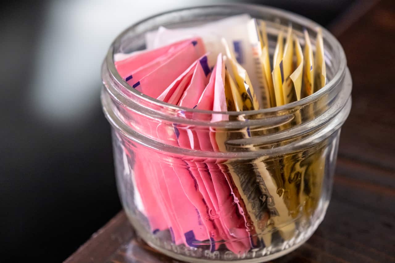 A jar of individual packets of artificial sweetener.