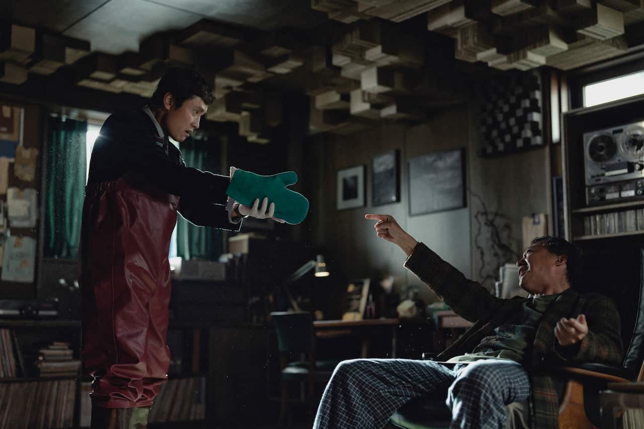 A man holding an oven mitt at another man's face.