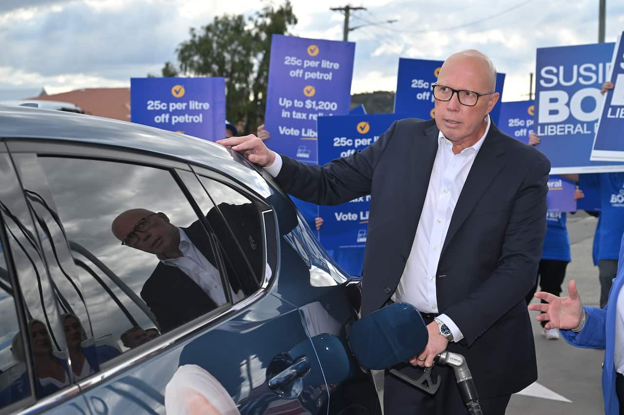 Peter Dutton is filling fuel in a car at a petrol pump.