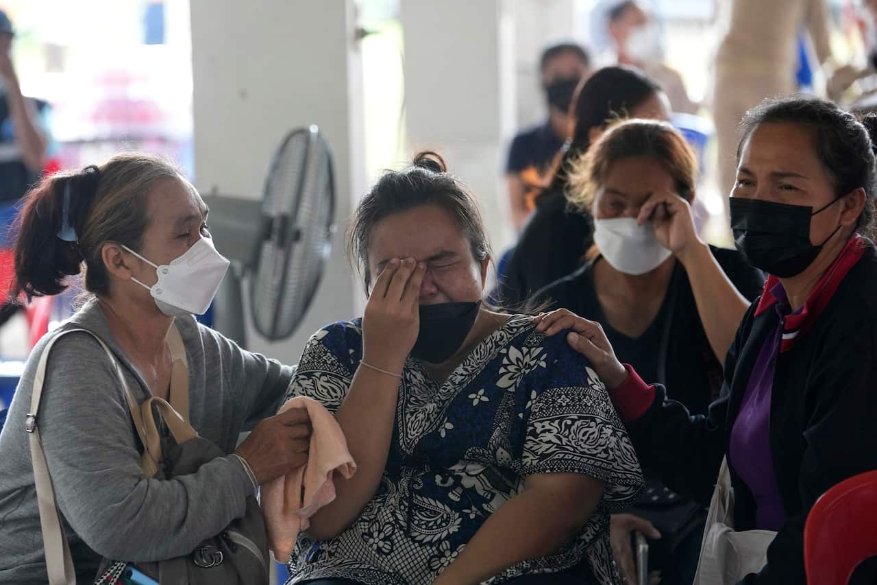 Four Thai women in face masks, crying