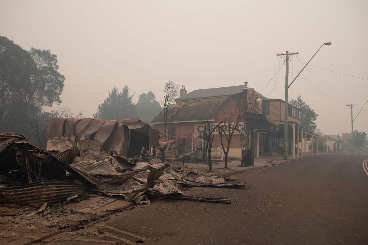 A burned out building and smoke covering a street.