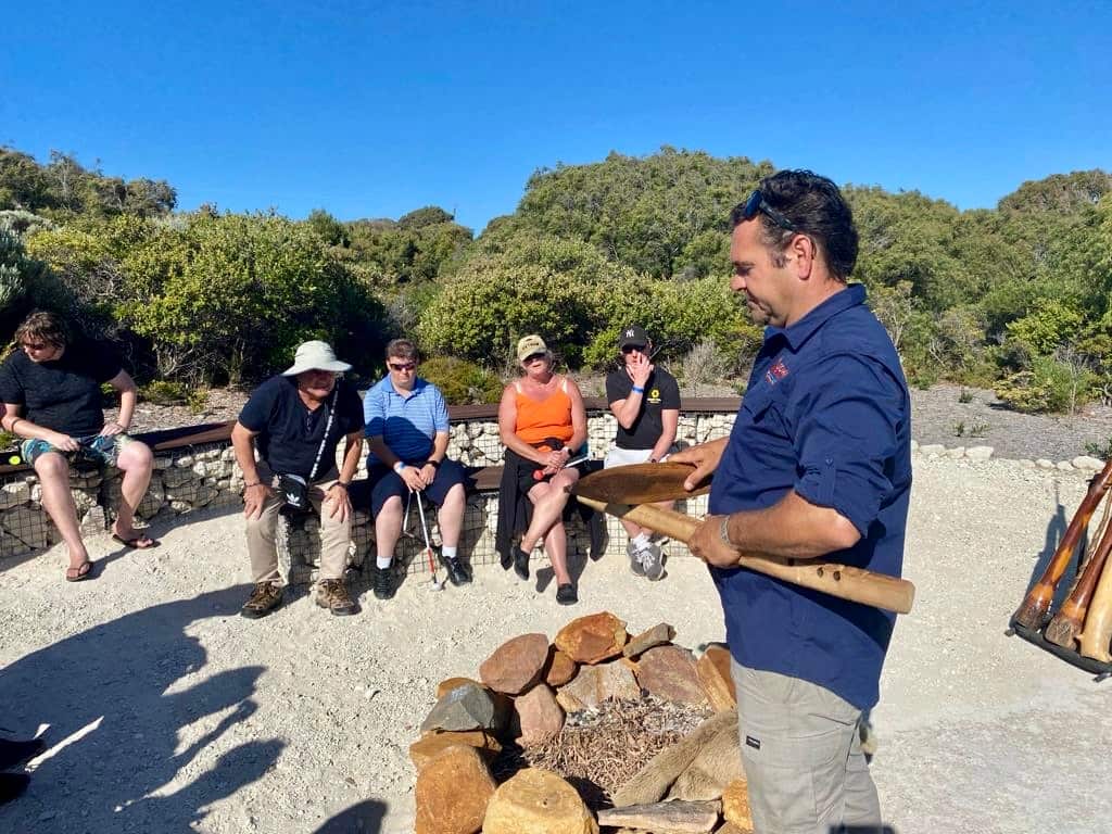 A group of visually impaired adults around a campfire. 