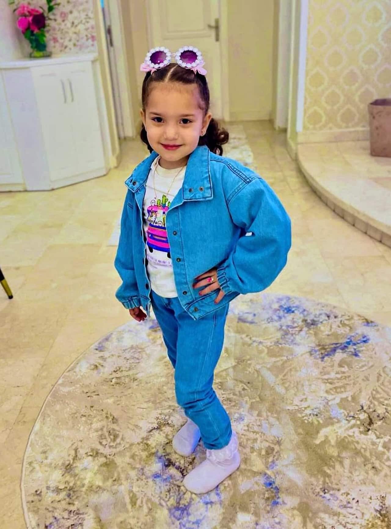A young girl wearing a blue denim jacket and jeans.
