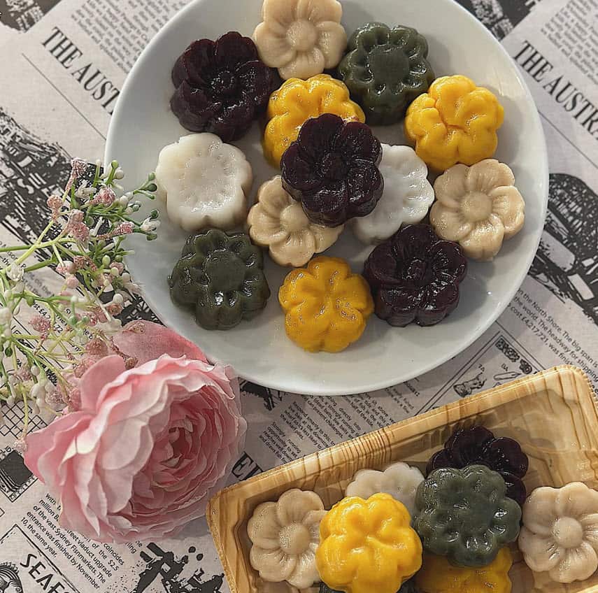 A selection of colourful round songpyeon displayed in a plate and a basket