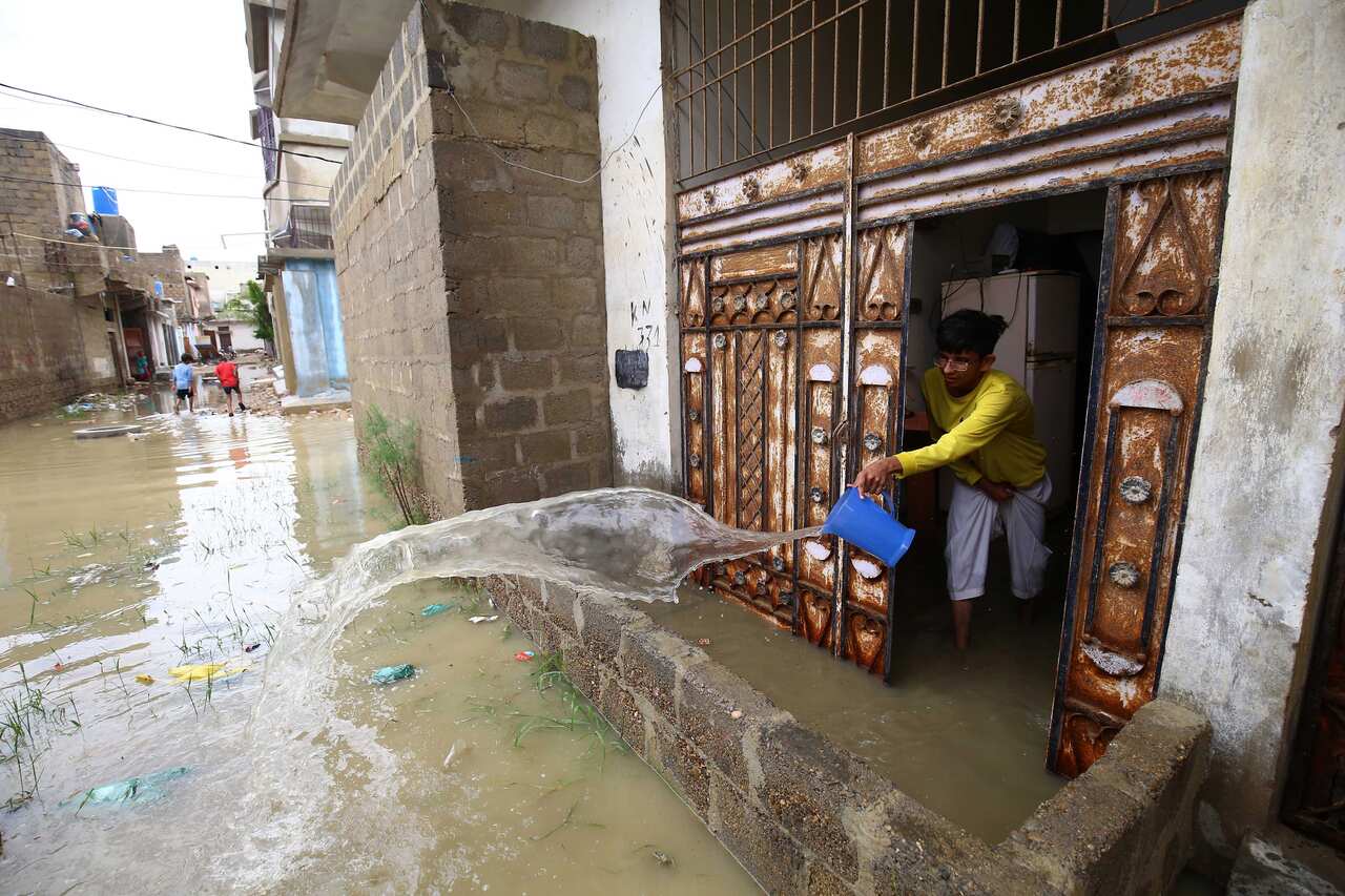 A man pours water out of his flooded home