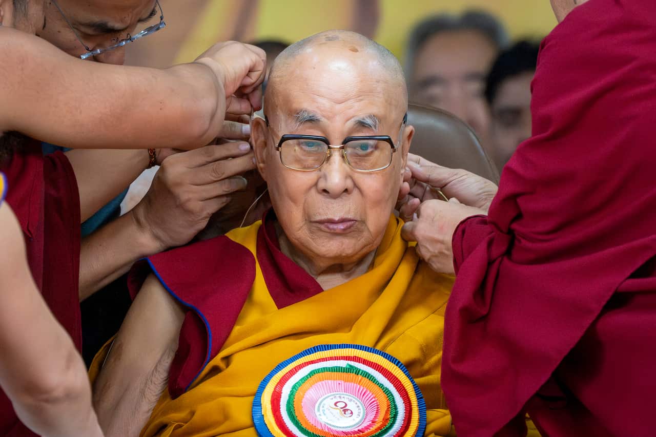 Many monks surround the Dalai Lama and equip him with a microphone ahead of his 90th birthday celebrations in Dharamshala, India.
