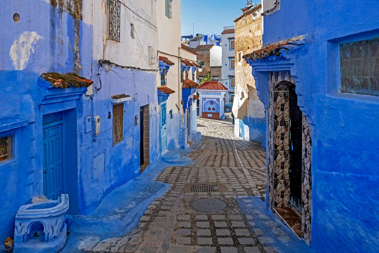 Narrow alleyway with blue walls, houses and doors in medina.