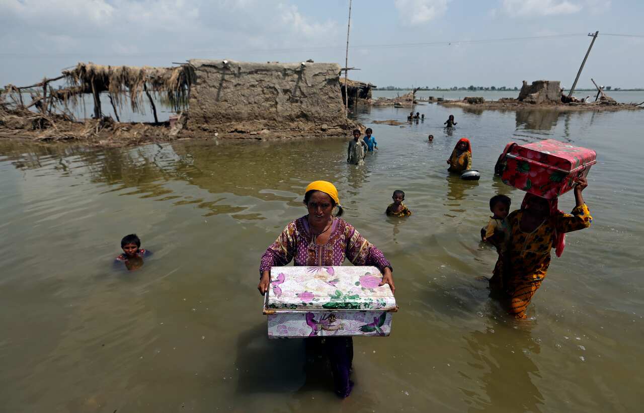 People wading in floodwaters carrying belongings