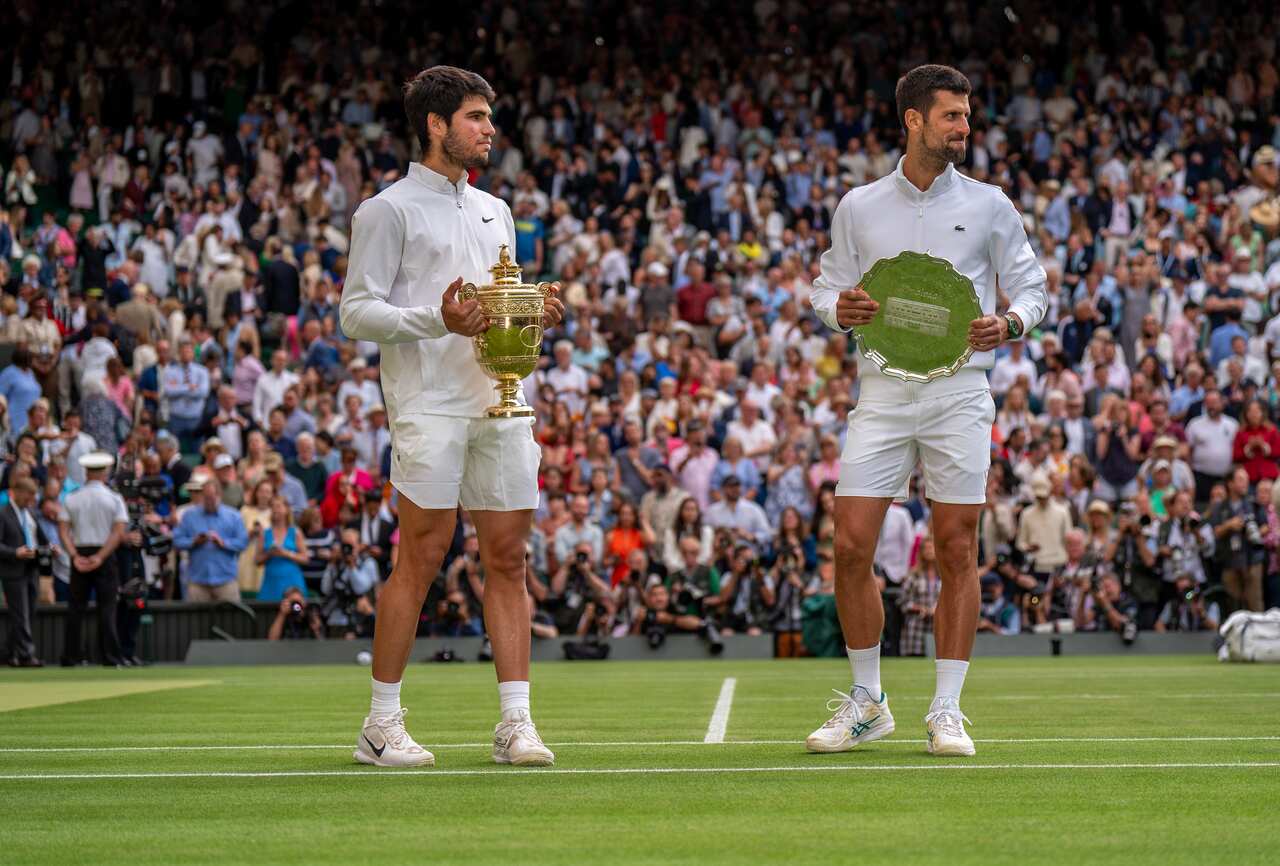 Two man pose for photo holding trophies.