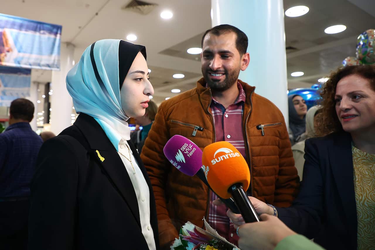 A woman speaking into media microphones.