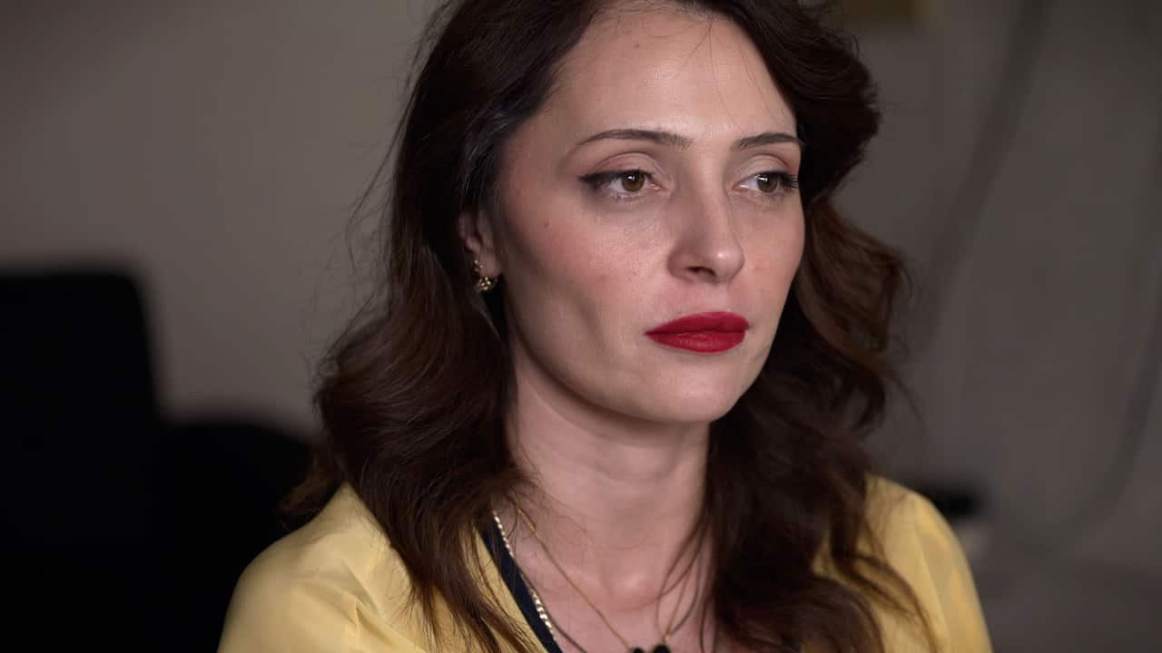 A woman with long wavy dark hair wearing red lipstick