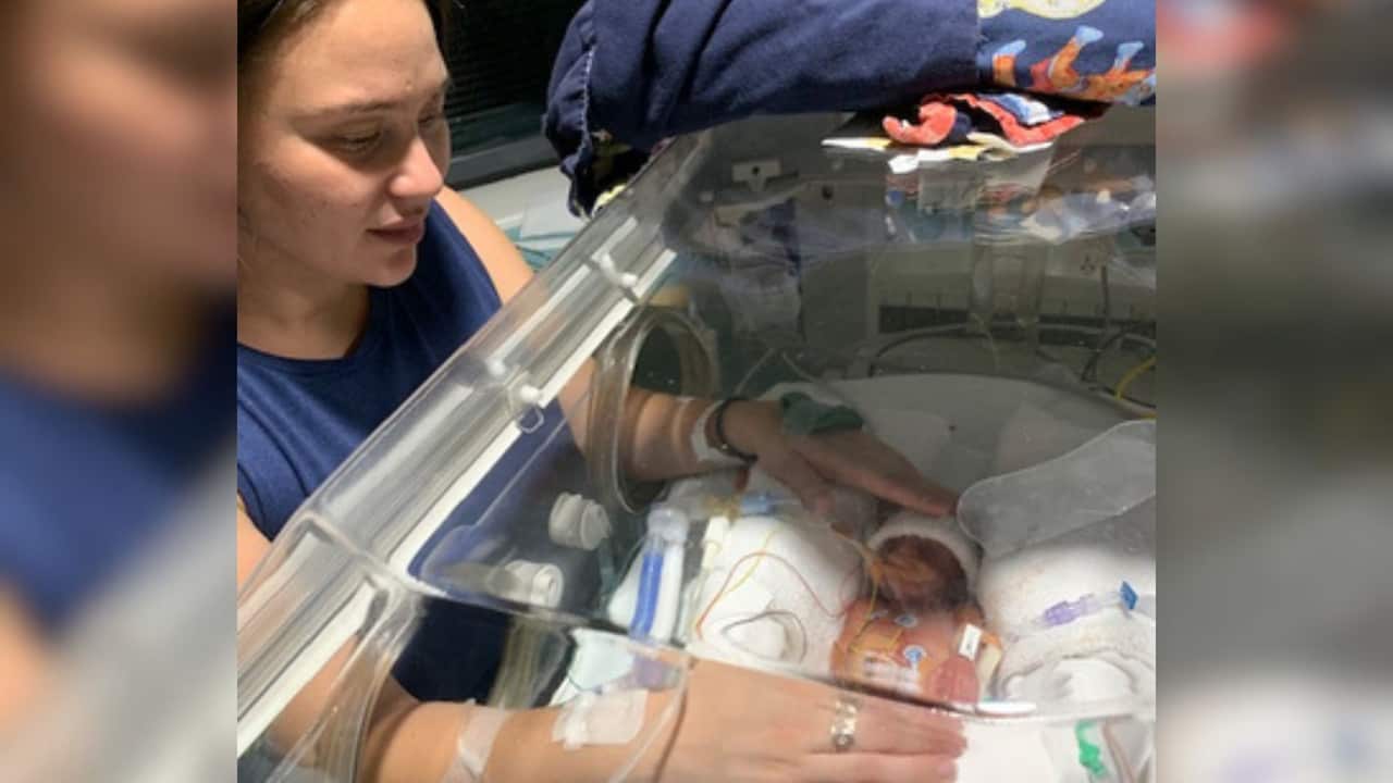 a woman touching a premature baby in a ventilator in a hospital