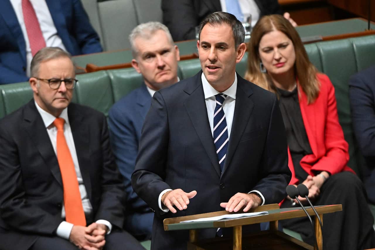 A man wearing a suit and tie makes a speech. 