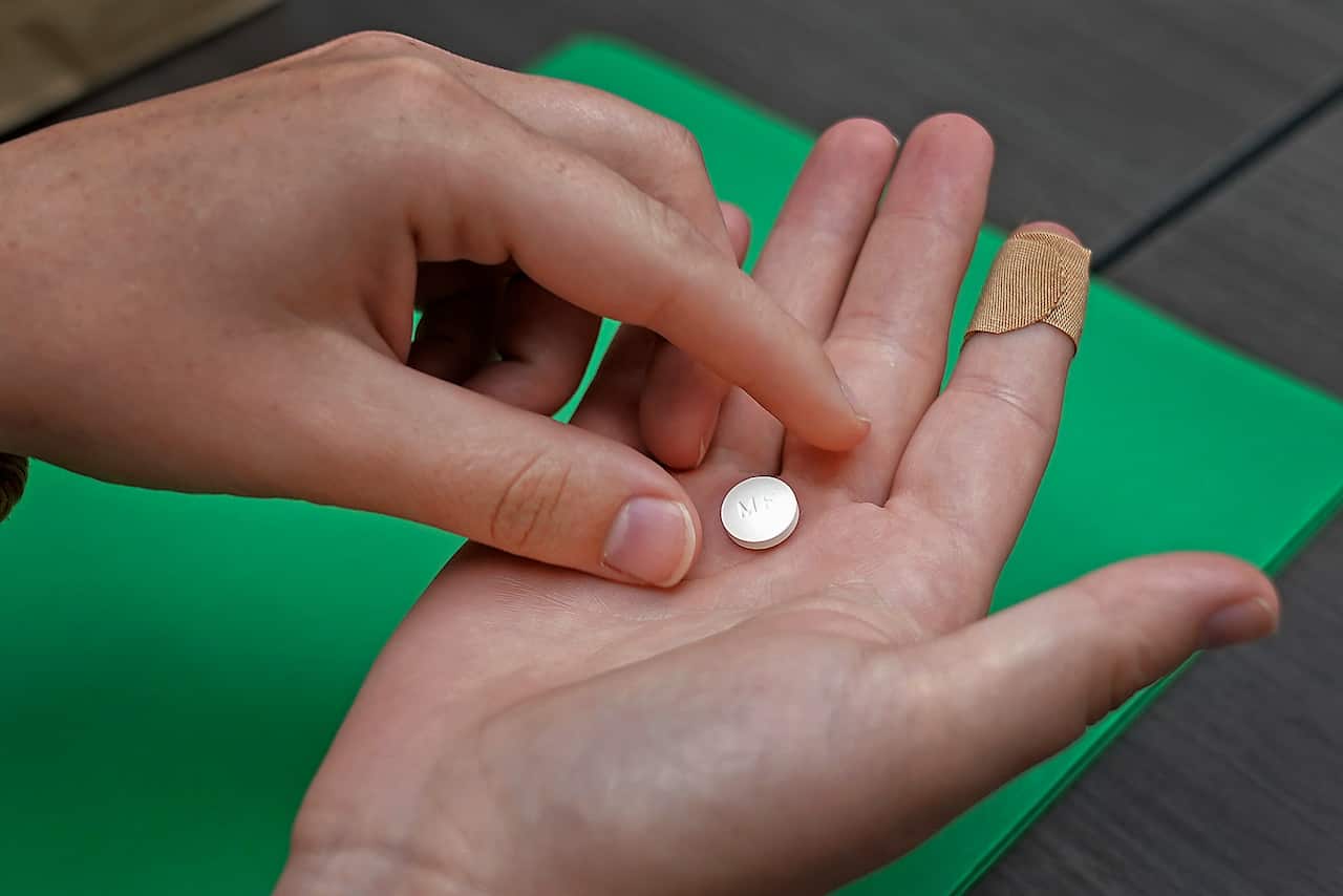 A person holding a pill in their hand. 