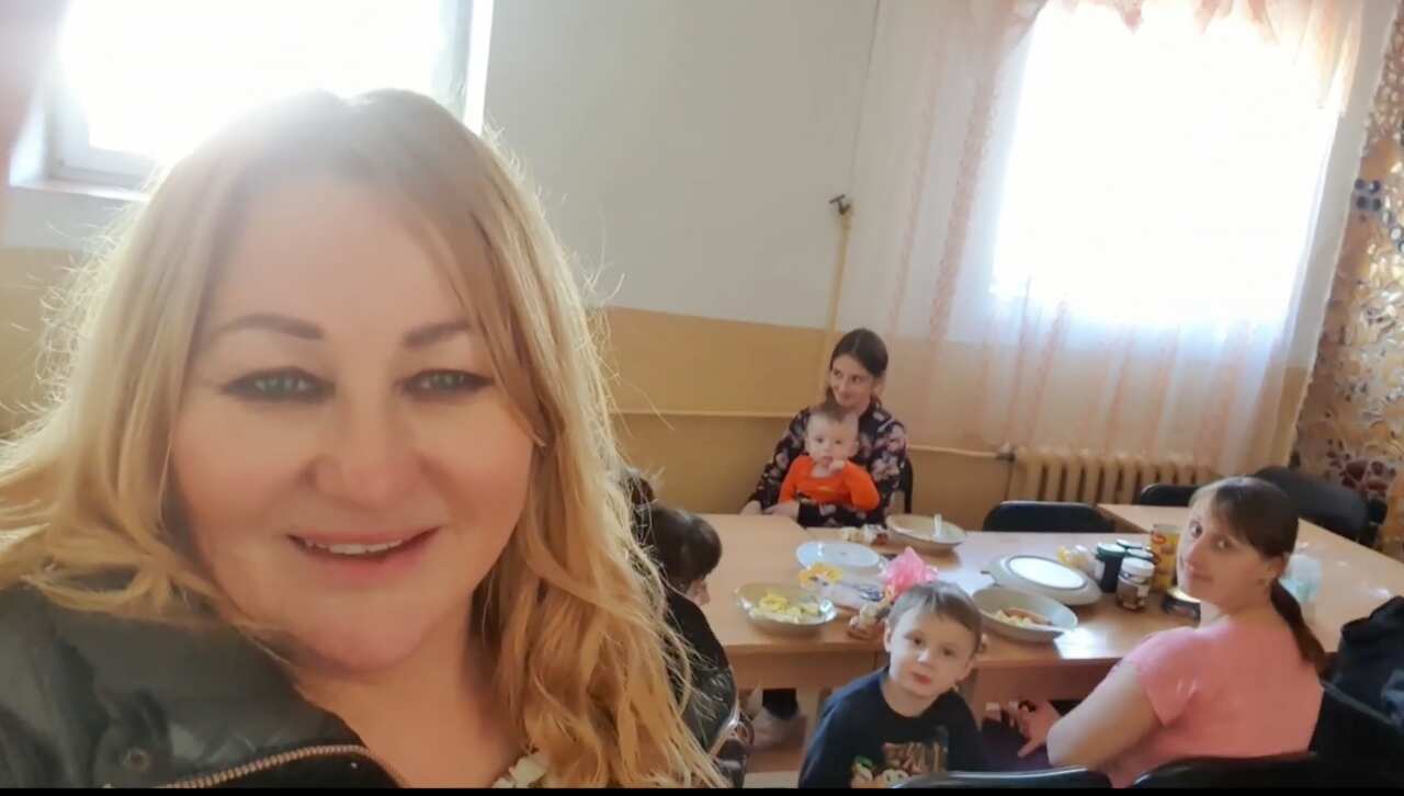 Basia takes a selfie of women and children sitting at a table