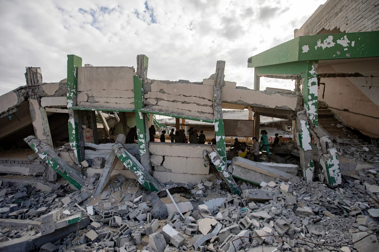 Palestinian children learn in a destroyed classroom